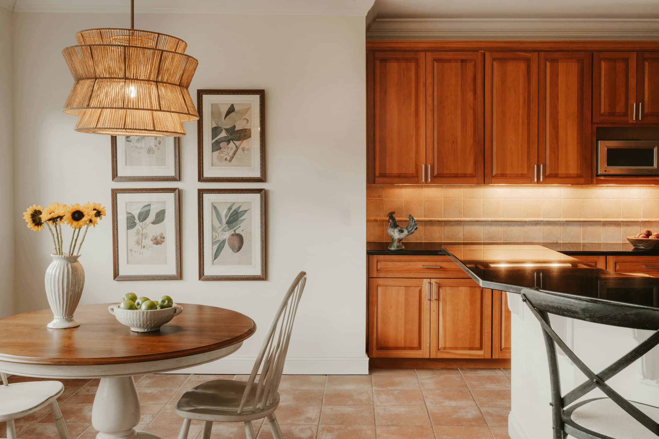 Warm wood kitchen cabinetry with detailed millwork and a woven pendant light.